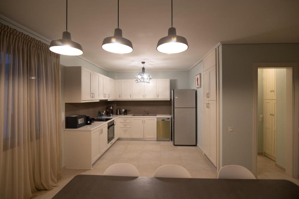 a kitchen with white cabinets and a black refrigerator at Lampetos Houses Molyvos in Mythimna