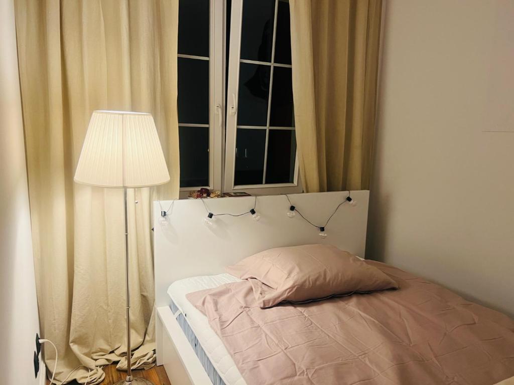 een slaapkamer met een bed met een lamp en een raam bij Apartament Villa Park in Ełk
