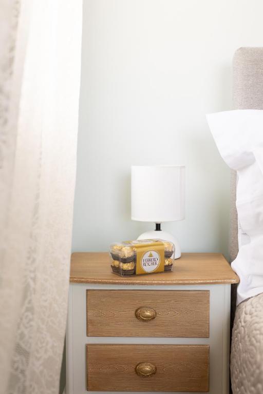 a nightstand with a lamp on it next to a bed at Lampetos Houses Molyvos in Mythimna