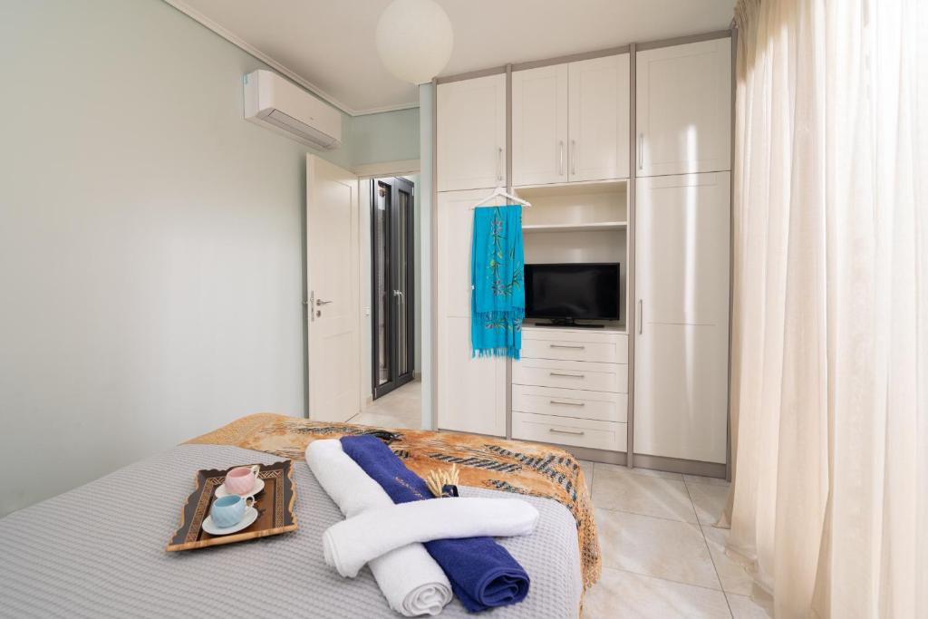 a bedroom with a bed with towels and a television at Lampetos Houses Molyvos in Mythimna