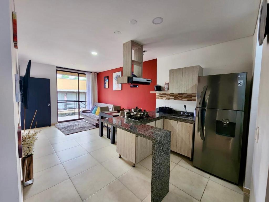 eine Küche mit roten Wänden und einem Kühlschrank aus Edelstahl in der Unterkunft Apartamento Campestre cerca a Armenia y Parque del Cafe E306 a 5 minutos del Aeropuerto en La Tebaida in Armenia