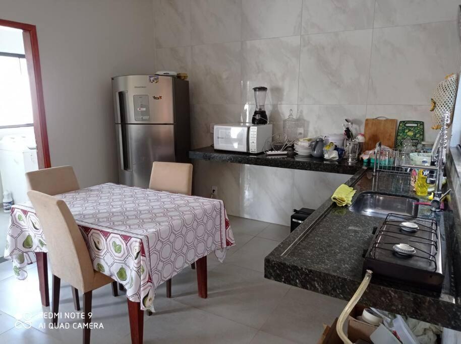 eine Küche mit einem Tisch, einem Herd und einem Kühlschrank in der Unterkunft casa com piscina, 03 quartos, ótima localização! in Bonito