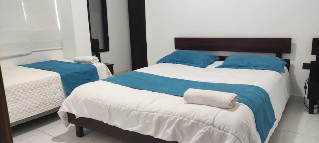 a bedroom with two beds with blue and white sheets at Hotel Mykonos Manta in Manta