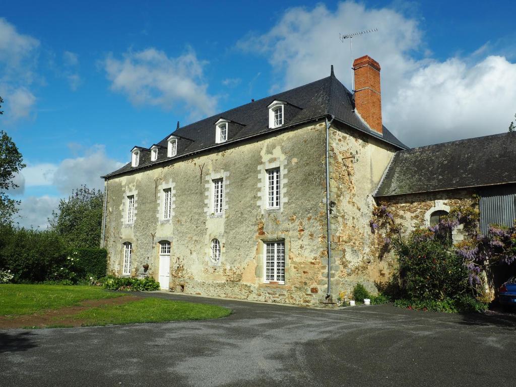 stary kamienny budynek z czarnym dachem w obiekcie Les Grands-Aulnais w mieście Cossé-le-Vivien