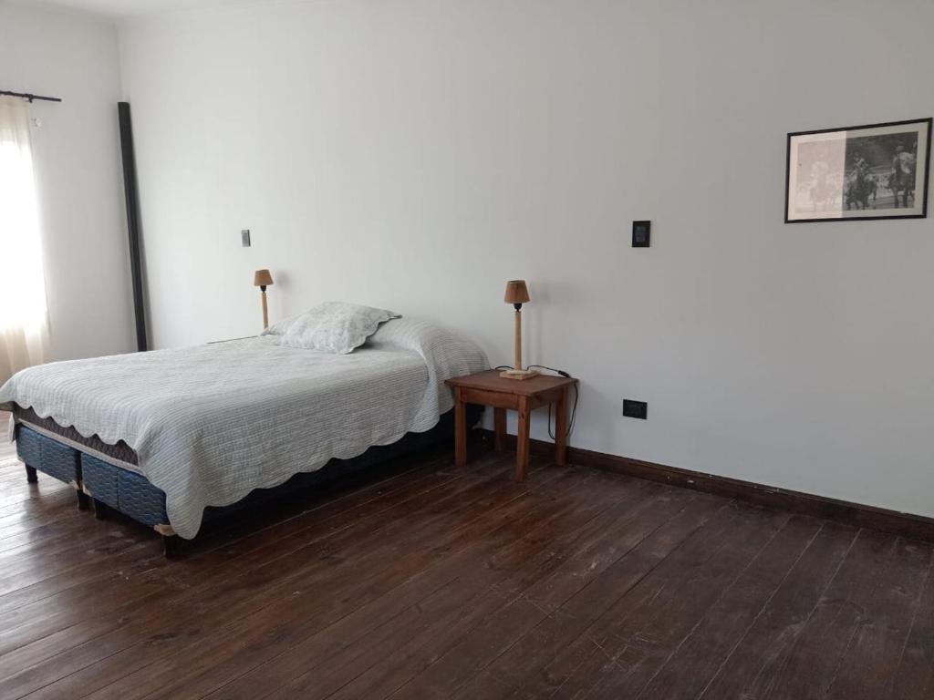 1 dormitorio con cama y mesita de noche con mesa en Departamentos Casco Urbano San Antonio de Areco en San Antonio de Areco