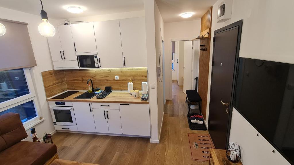 Elle comprend une petite cuisine avec des placards blancs et un évier. dans l'établissement Apartmani Šišarka Jahorina, à Jahorina