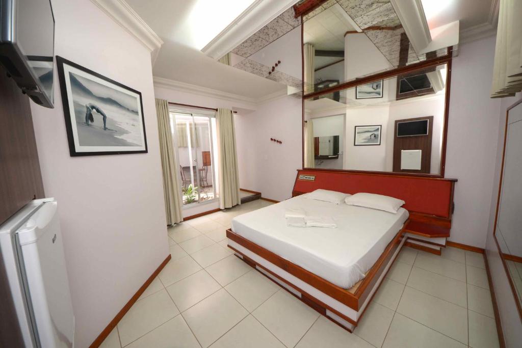 Schlafzimmer mit einem Bett und einem Wandspiegel in der Unterkunft PARK MOTEL in Indaiatuba