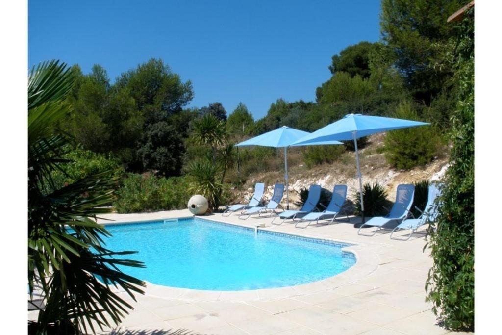 een zwembad met ligstoelen en parasols bij Villa provençale 8 personnes in Ventabren