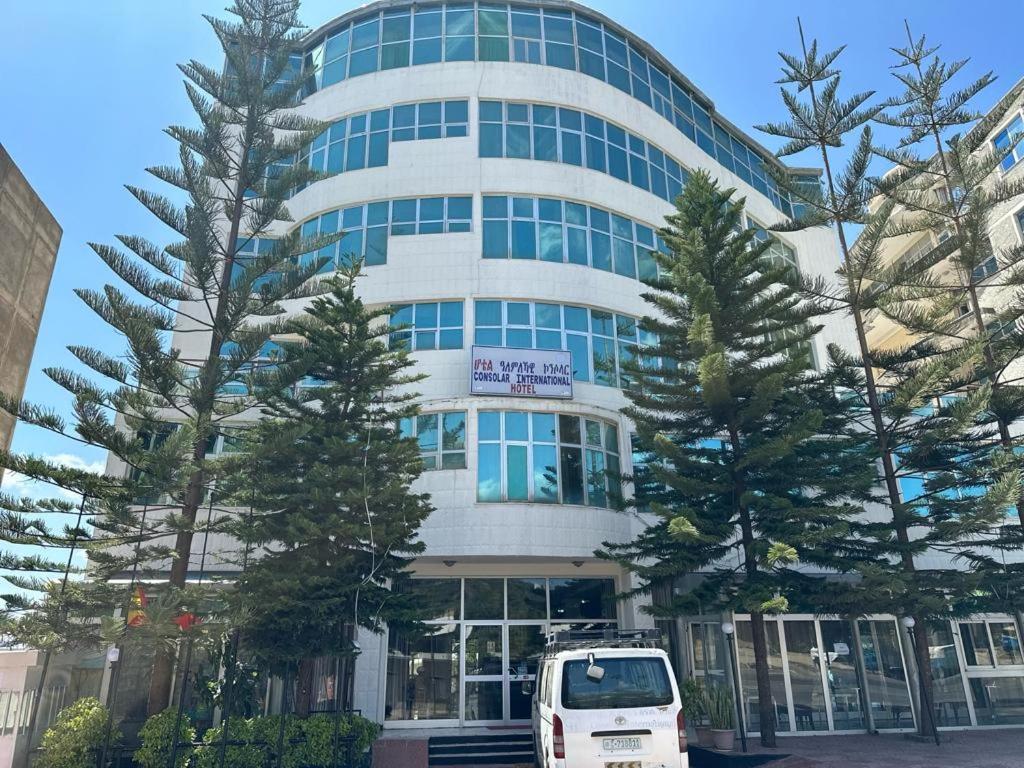 una furgoneta blanca estacionada frente a un edificio en Consolar International Hotel, en Āksum