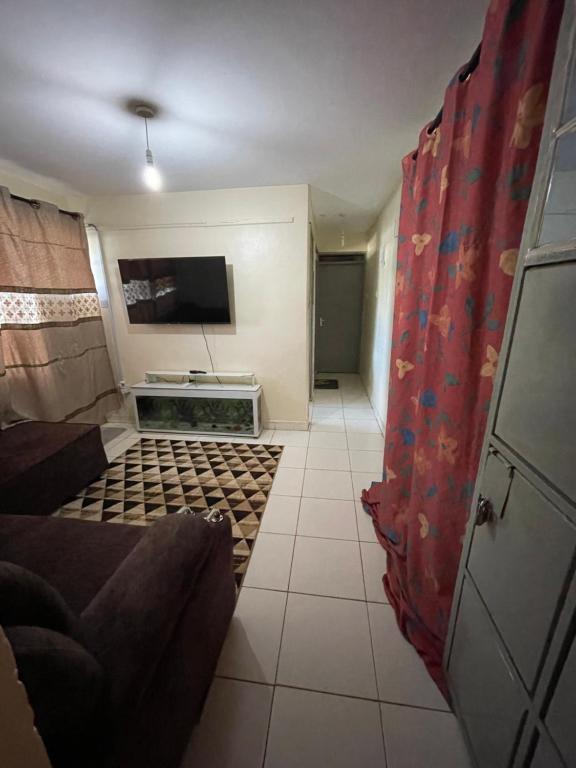 a living room with a couch and a tv in a room at Tawakal airbnb in Thika