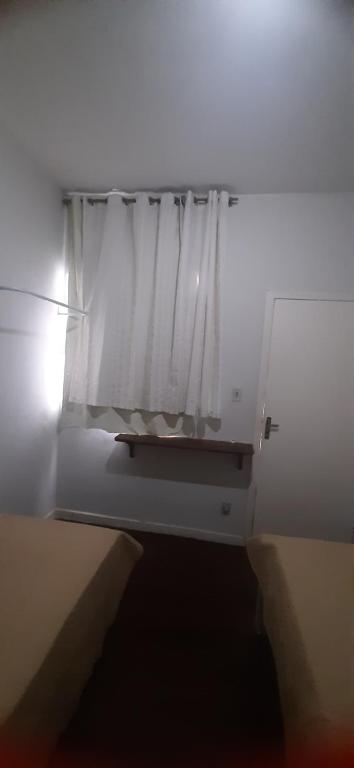 een raam met een wit gordijn in een kamer bij Lugar Certo Tranquilo in Itabira
