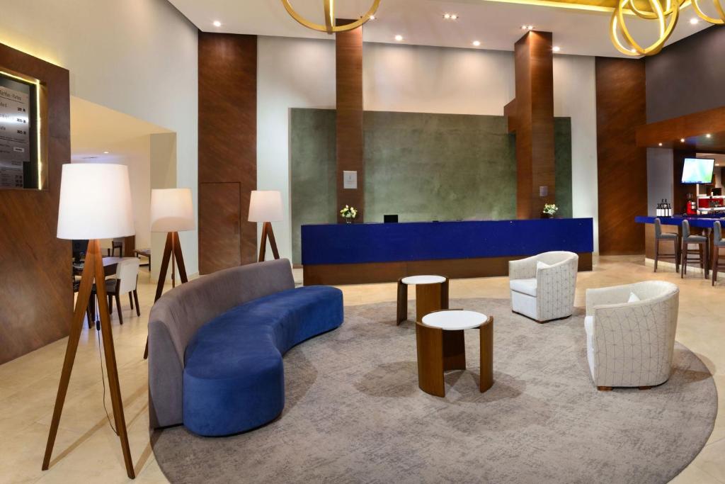 eine Lobby mit einem blauen Sofa, Stühlen und Tischen in der Unterkunft Gran Hotel de Puebla by HNF in Puebla