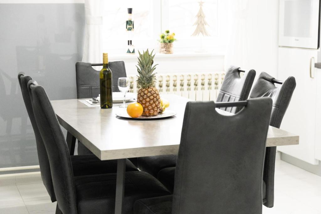 een eettafel met een ananas en een fles wijn bij Maris in Osijek