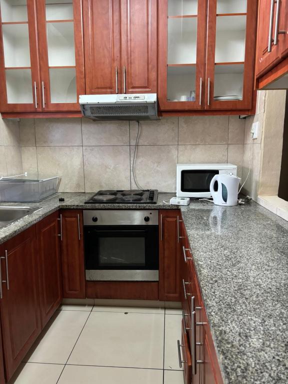 a kitchen with wooden cabinets and a stove and a microwave at Gardenlea in Durban