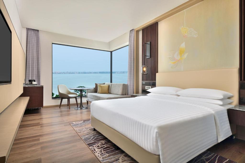 ゴーラクプルにあるCourtyard by Marriott Gorakhpurのベッドルーム(大きな白いベッド1台、大きな窓付)