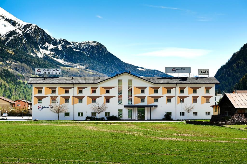 ein großes Gebäude mit Bergen im Hintergrund in der Unterkunft Motel Gottardo Sud in Piotta
