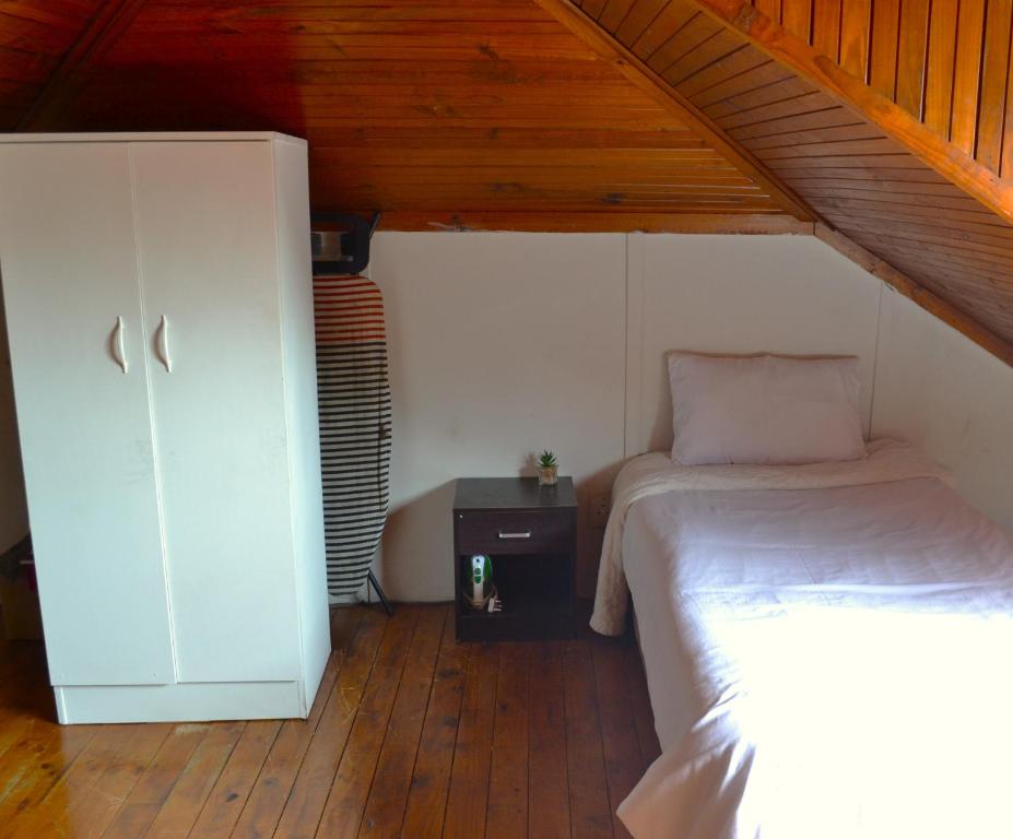 a bedroom with a bed and a cabinet in a attic at HOME AWAY FROM HOME in Cape Town
