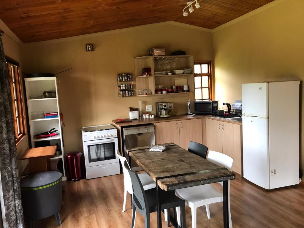 a kitchen with a wooden table and a white refrigerator at Acorn Log Home in Port Elizabeth