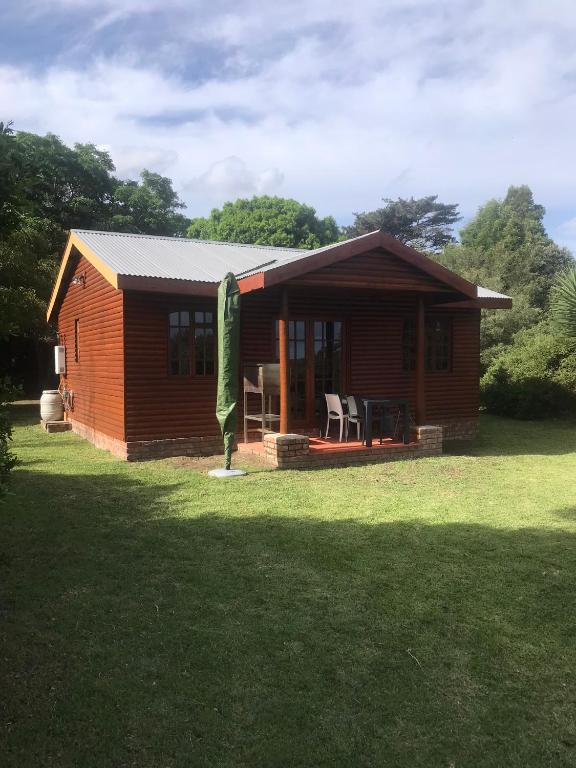 a small cabin with a grassy yard in front of it at Acorn Log Home in Port Elizabeth
