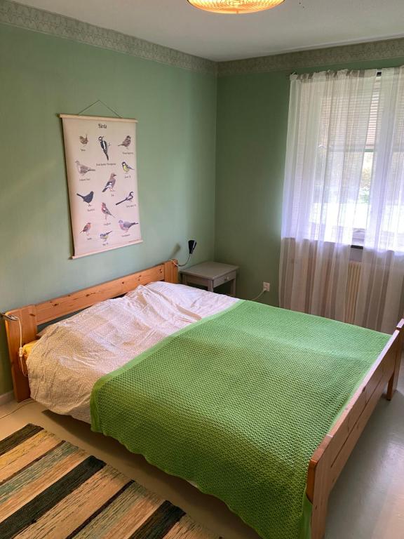 a bedroom with a bed with a green comforter at Fristad Hostel Vitsand in Gunsjögården