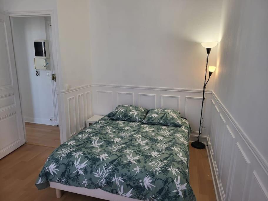 um quarto com uma cama com um edredão verde e branco em Appartement Accueillant em Vitry-sur-Seine