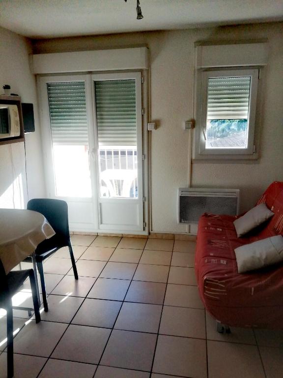 sala de estar con sofá rojo y 2 ventanas en Appartement, en Lamalou-les-Bains