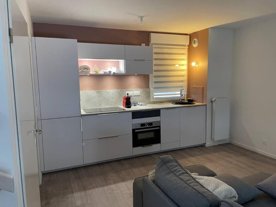 een keuken met witte kasten en een bank in een kamer bij Mi Casa in Achères