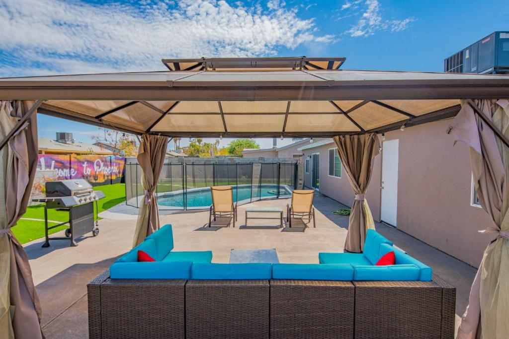 un patio con muebles azules bajo un pabellón en Phoenix Oasis with Outdoor Pool and Putting Green! en Phoenix