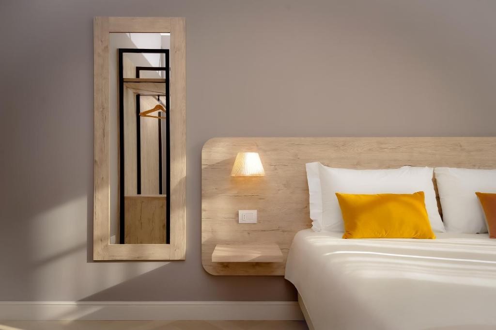 a bedroom with a bed with a yellow pillow and a mirror at Bergamo Inn 43 in Bergamo