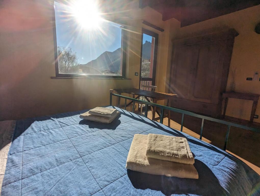 a bedroom with a bed with a window with the sun at Adagio Guesthouse in Caprie