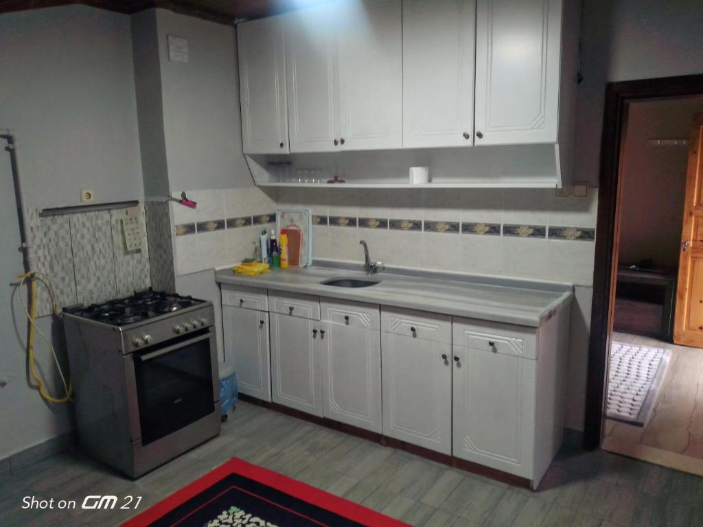 cocina con armarios blancos, fregadero y fogones en Rooftop apartment with a big garden, en Kocaeli