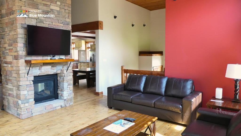 a living room with a leather couch and a fireplace at 109 Plater St in Blue Mountains