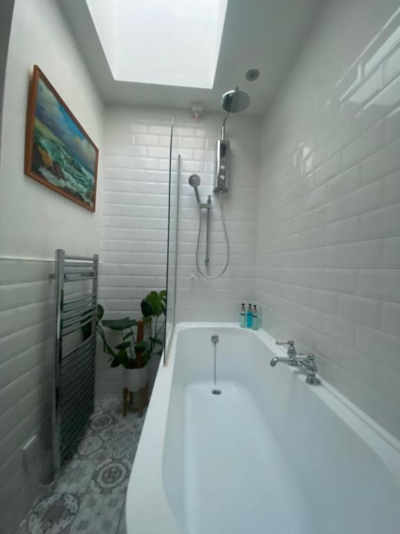 y baño blanco con bañera y ducha. en Longsands Hideaway, en Tynemouth
