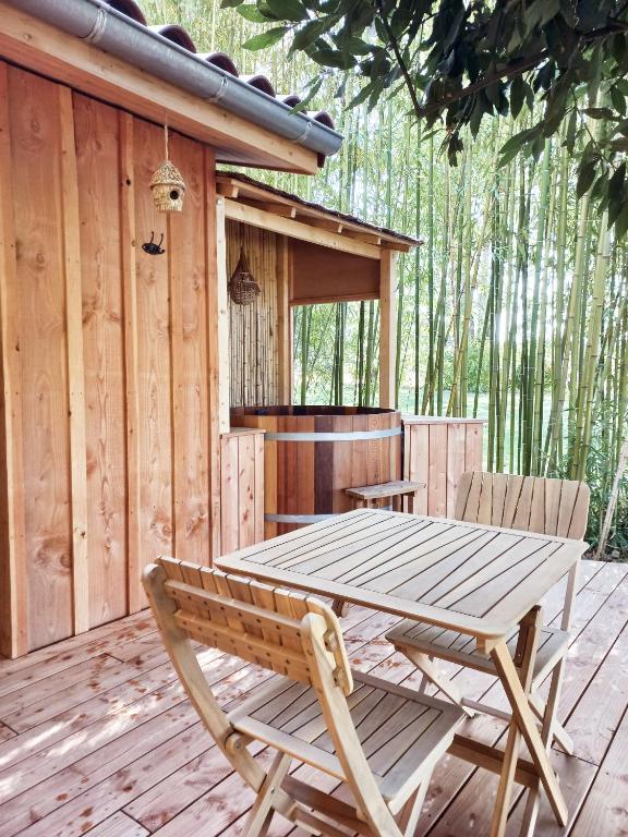 une table et des chaises en bois sur une terrasse en bois dans l'établissement maisonette et spa bois, à La Bégude-de-Mazenc