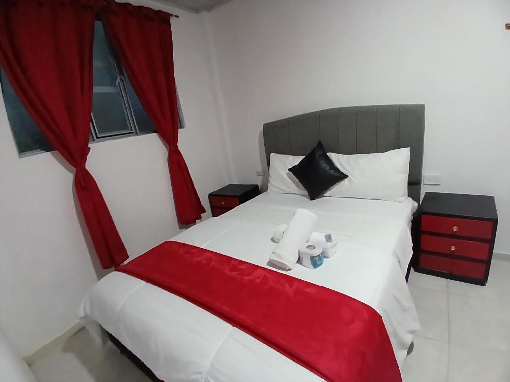 Schlafzimmer mit einem großen Bett und roten Vorhängen in der Unterkunft HOTEL ISMAEL de la VILLA in Tinjacá