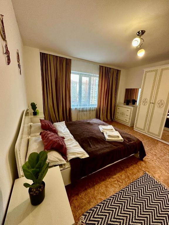 ein Schlafzimmer mit einem Bett und einem Tisch mit einer Pflanze in der Unterkunft ЖК Трилистник in Qaraghandy