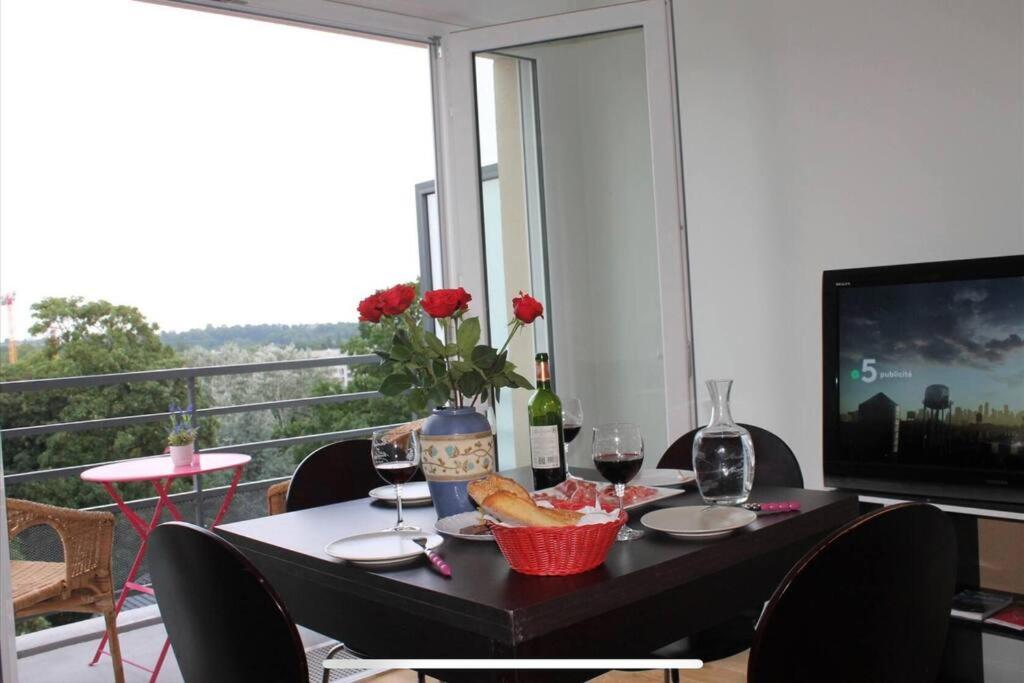 tavolo da pranzo con bicchieri da vino e televisore di Beau apartment Châtenay-Malabry a Châtenay-Malabry