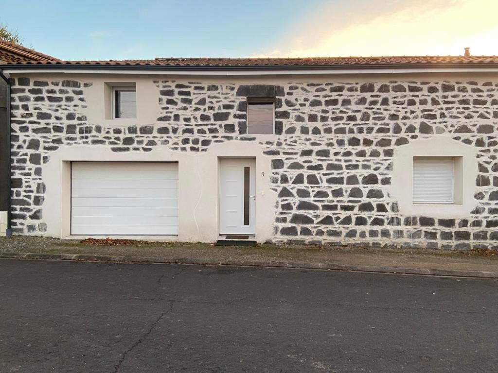 um edifício de pedra com duas portas de garagem em La grange de Céline 