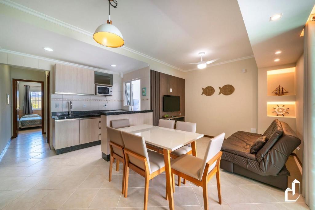 a kitchen and living room with a table and a couch at Residencial Maresias - 02 dormitórios in Bombinhas