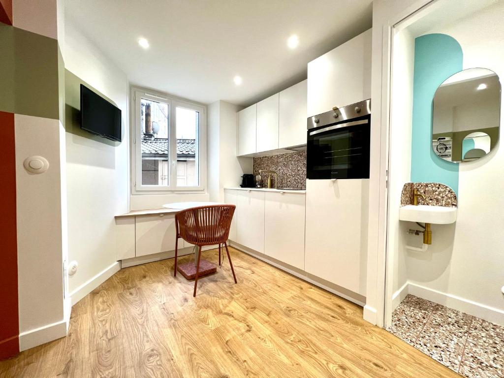 a kitchen with white cabinets and a table and a chair at La Loge Parisienne, 300m gare, Climatisation, Téléphérique in Grenoble