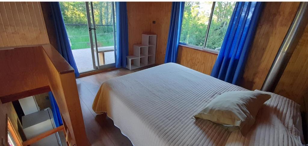 1 dormitorio con 1 cama blanca y 2 ventanas en Cabaña 3 personas Villarrica Pucón, en Pucón