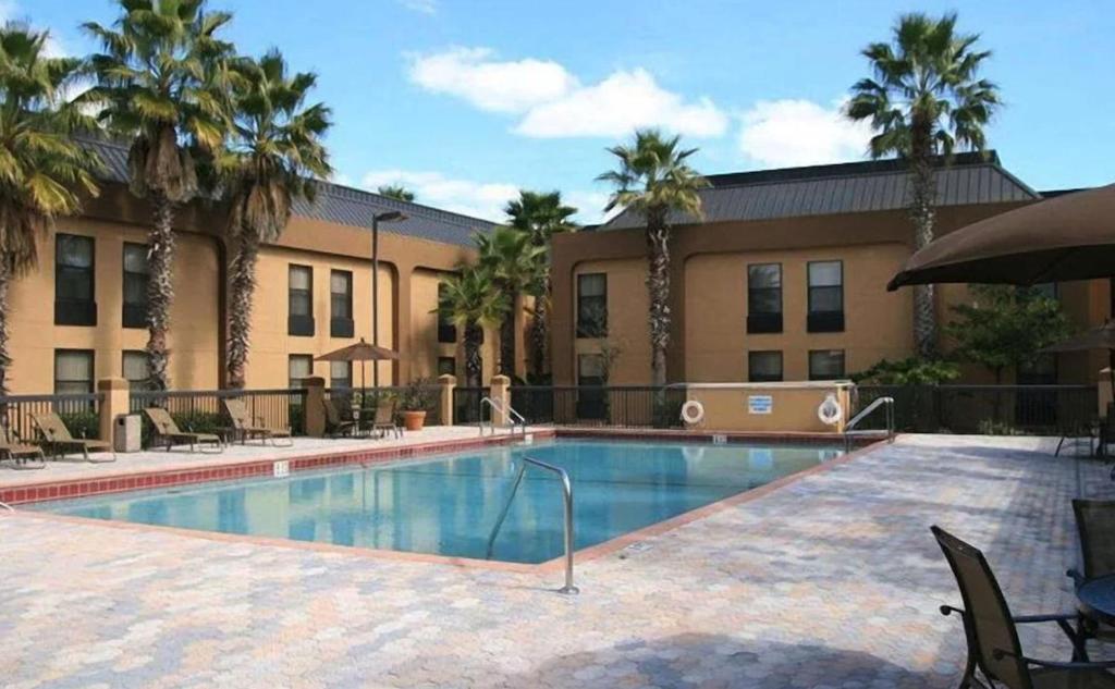 a swimming pool in front of a building with palm trees at Orlando Palms in Orlando