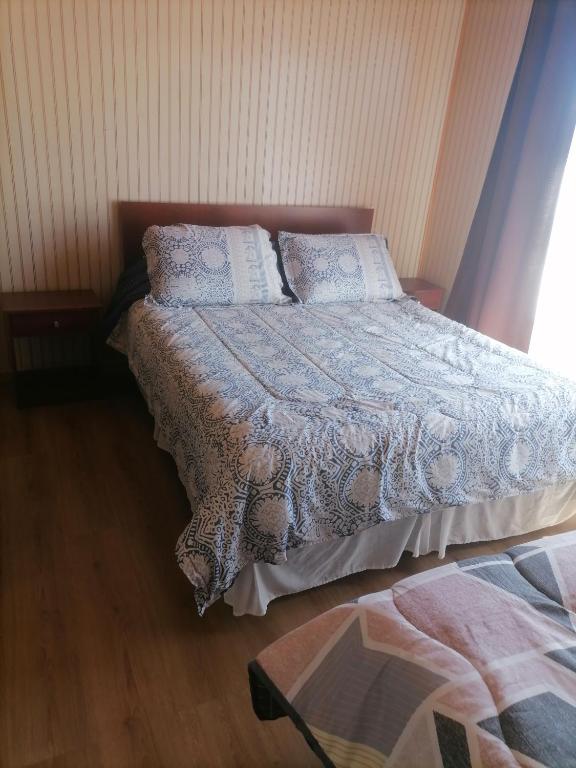 1 dormitorio con 1 cama con manta y almohadas en herencia de pioneros, en Coyhaique
