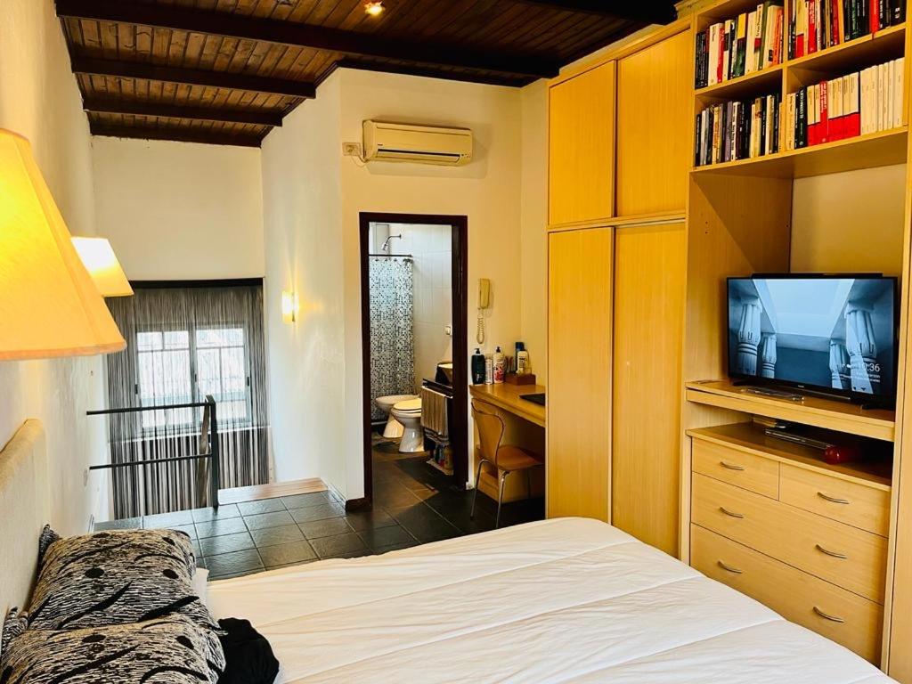 1 dormitorio con 1 cama, TV y escritorio en La casita en Paso de los Libres