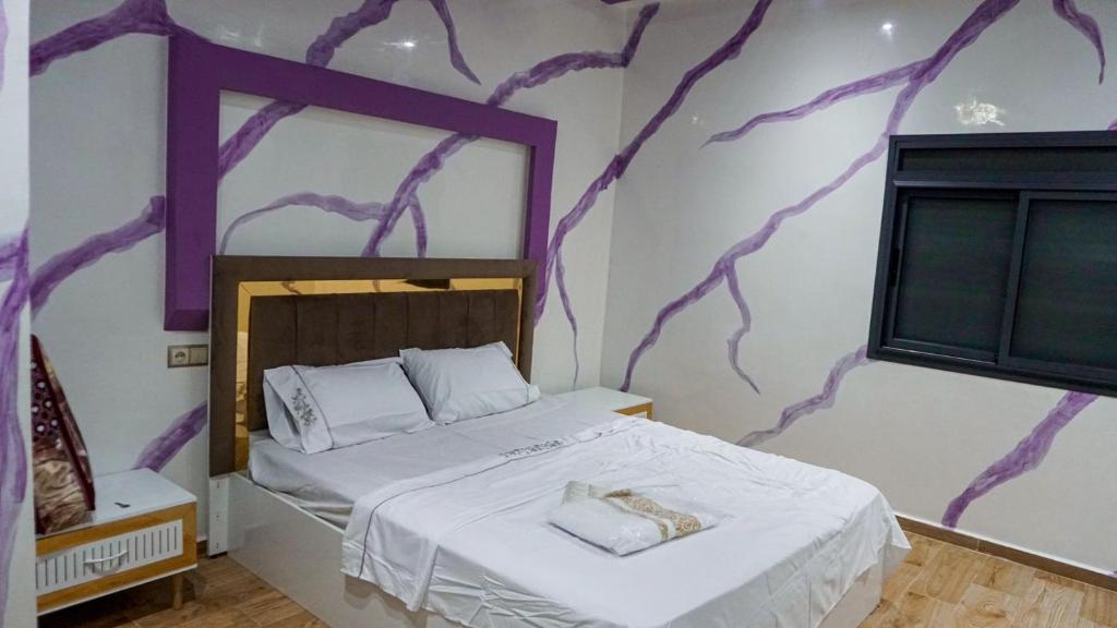 ein Schlafzimmer mit einem Bett mit einer lila Wand in der Unterkunft العيون شارع 24 نوفمبر قرب قروان in El Aaiún