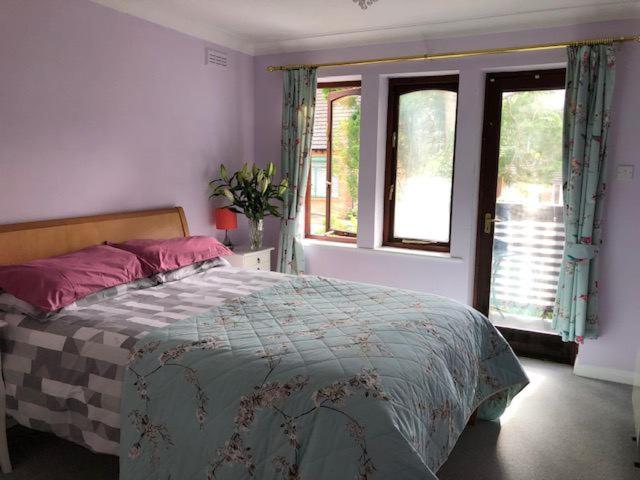 a bedroom with a bed and two windows at Cozy bedroom in well equipped apartment in Leatherhead