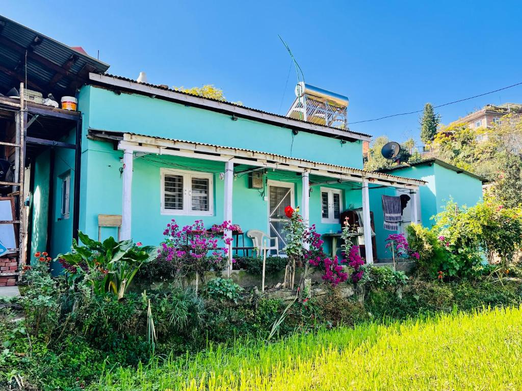 una casa azul con flores delante en Dulal’s Homestay en Godāvari