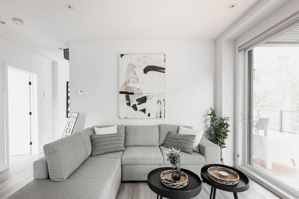 een woonkamer met een bank en 2 tafels bij Modern Luxurious Chalet near Tremblant in La Conception