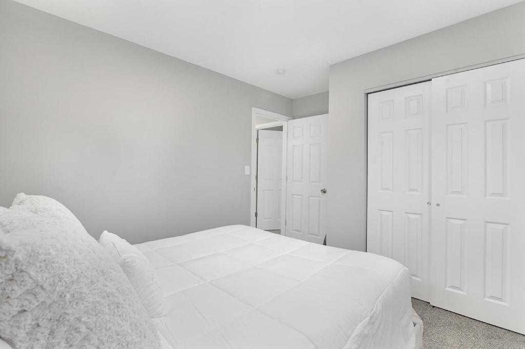 a white bedroom with a white bed and white doors at Relax and Play in Akron