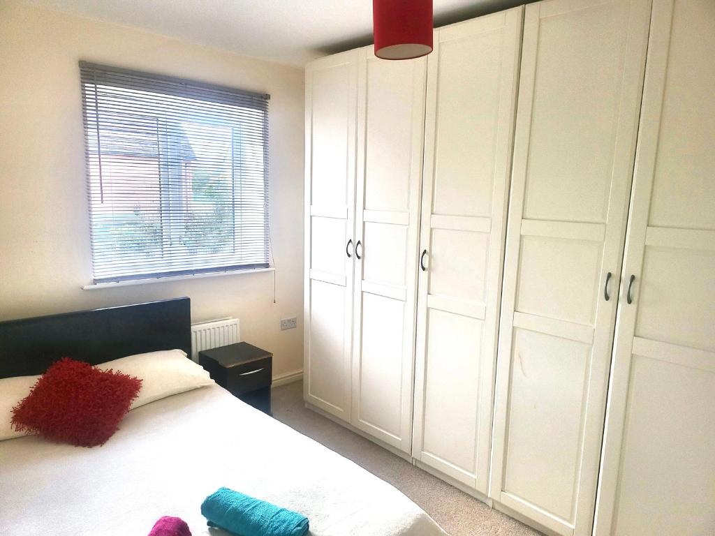 um quarto com uma cama com armários brancos e uma janela em The Haven Comfort em Harold Wood